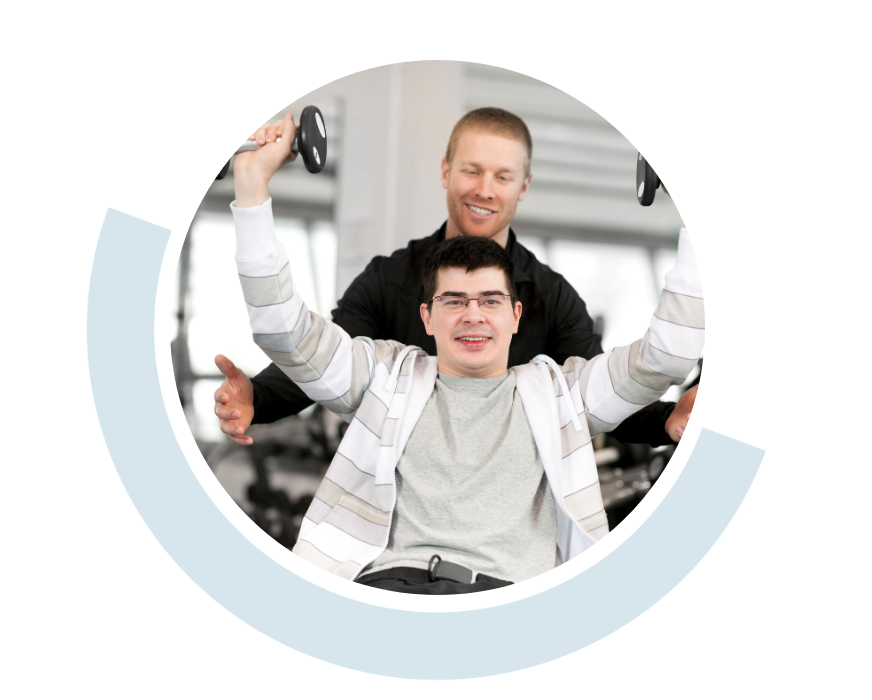 Website header graphic with curved light blue accents, featuring a circular photo of a smiling young man seated in front of a support person. The young man has both arms raising weights enthusiastically while the person behind him smiles.