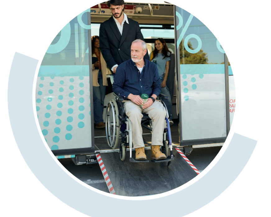Website header graphic with a pale background and curved light blue accents, featuring a circular photo of an older man in a wheelchair positioned at the entrance of an accessible public transport vehicle with another person suppoting them from behind the wheelchair.