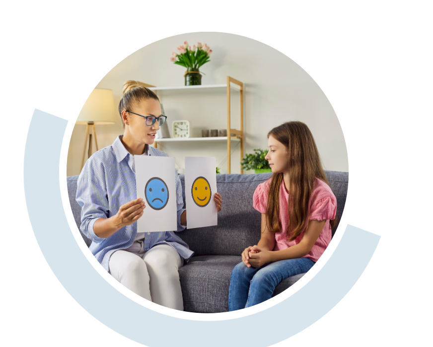 Website header graphic with a pale background and curved teal accents, featuring a circular photo of a counsellor speaking with a young girl seated opposite her in a comfortable room, showing her pictures of happy and sad smiley faces.