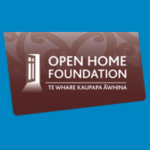 Open Home Foundation logo with the image of an open door, white text reading “OPEN HOME FOUNDATION” and smaller text reading “TE WHARE KAUPAPA ĀWHINA” on a brown background with a subtle decorative pattern.