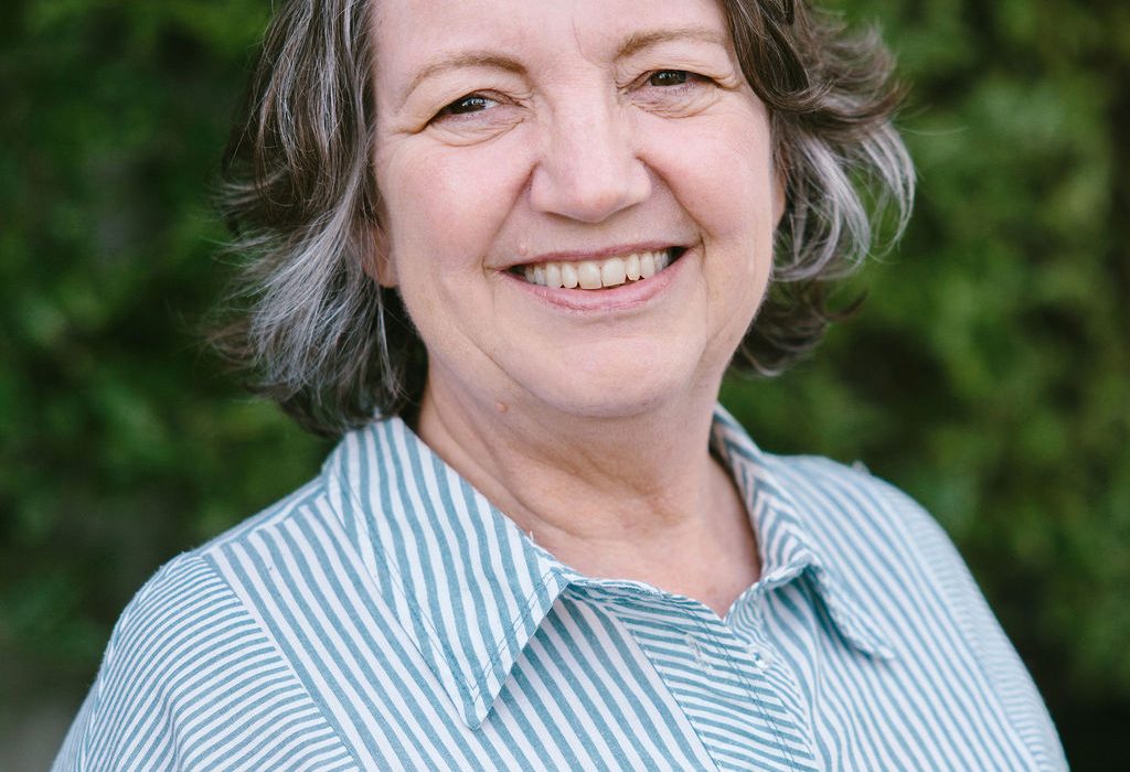 Woman with brown gray hair wearing a green and white striped shirt