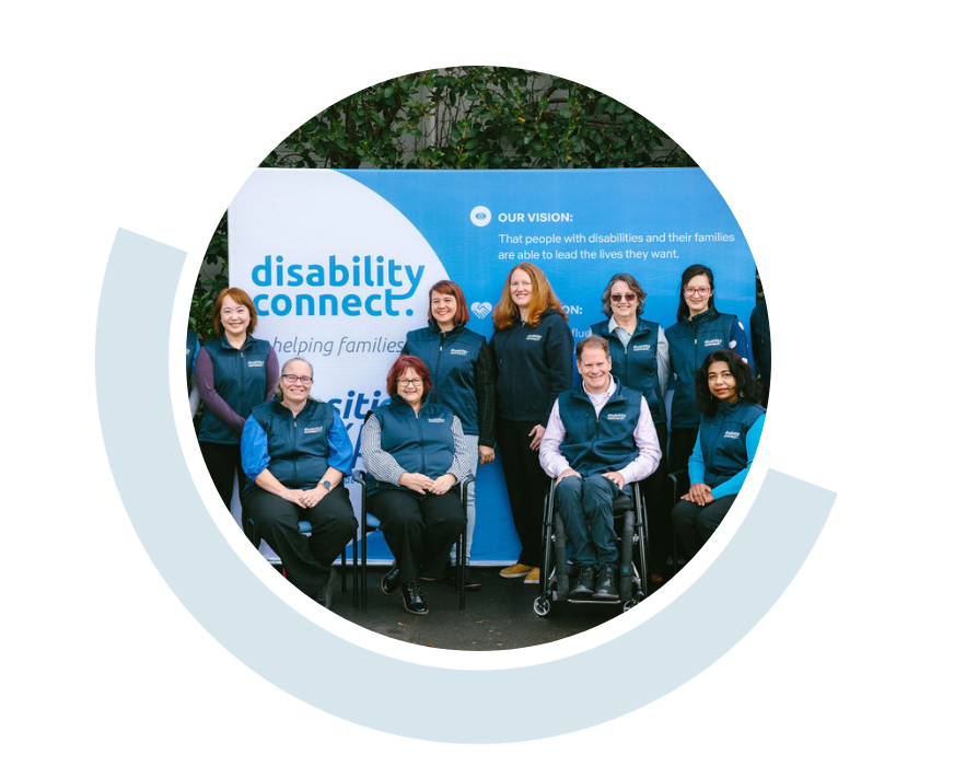 Website header graphic with a pale background and curved light blue accents, featuring a circular group photo of Disability Connect staff gathered together and smiling in front of a blue Disability Connect backdrop.