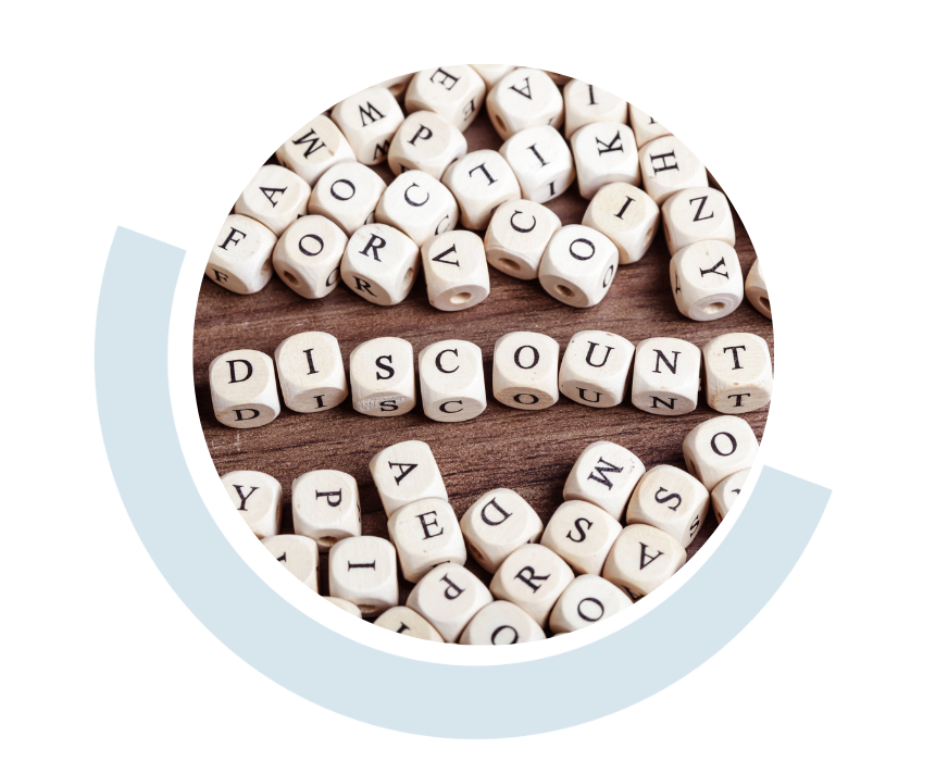 Website header graphic with a pale background and curved light blue accents, featuring a circular close-up of wooden letter cubes arranged on a table, with the word “DISCOUNT” spelled out across the centre.