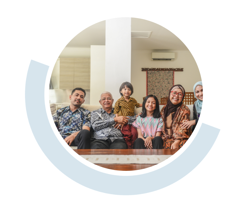 Website header graphic with a pale background and curved light blue accents, featuring a circular photo of a family of six, from a toddler to older adults, gathered together indoors and smiling towards the camera; two women wearing head scarves.