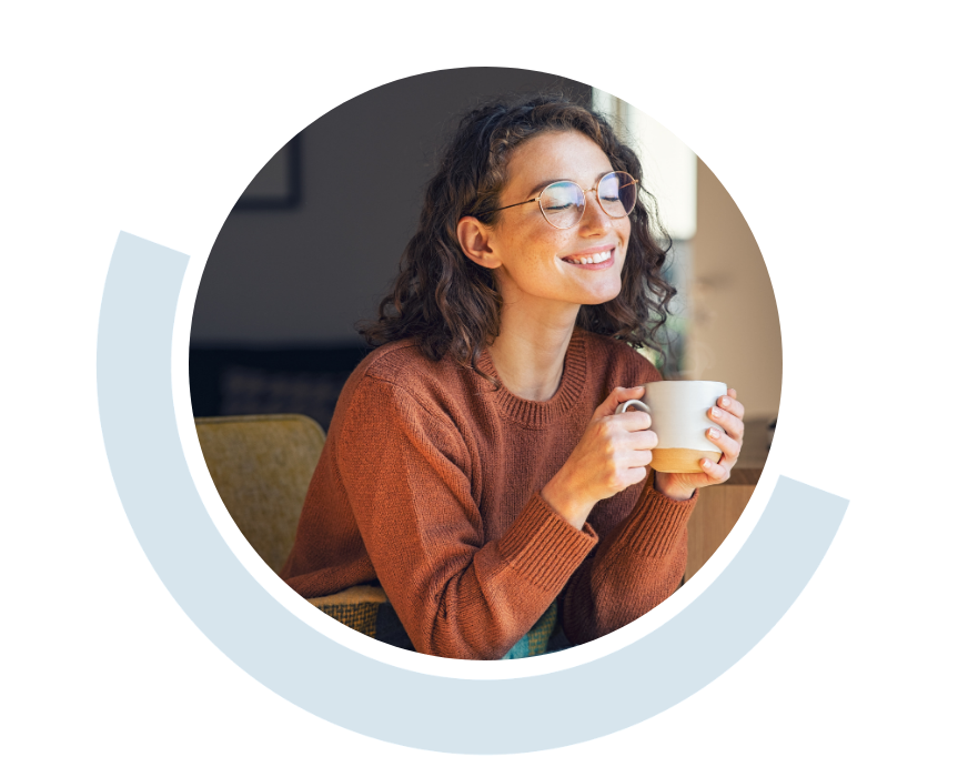 Website header graphic with a pale background and curved light blue accents, featuring a circular photo of a smiling woman wearing glasses and holding a mug while relaxing in a comfortable indoor setting.