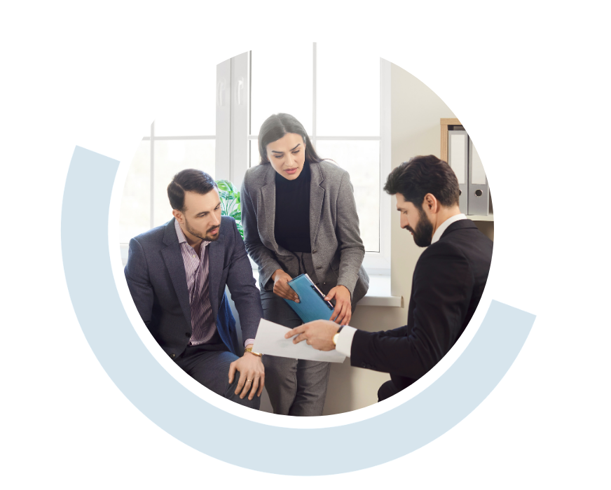 Website header graphic with a pale background and curved light blue accents, featuring a circular photo of three professionals discussing documents together during a meeting.