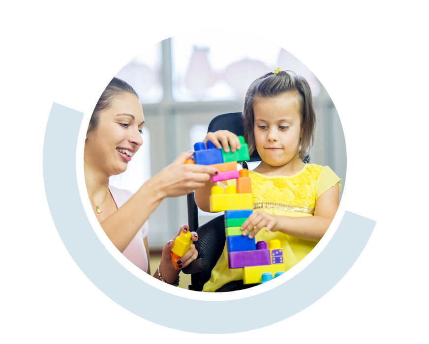 Website header graphic with a pale background and curved light blue accents, featuring a circular photo of a woman supporting a young child as they play with brightly coloured building blocks.
