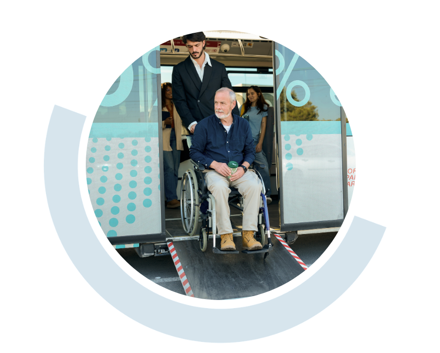 Website header graphic with a pale background and curved light blue accents, featuring a circular photo of an older man in a wheelchair positioned at the entrance of an accessible public transport vehicle with another person suppoting them from behind the wheelchair.